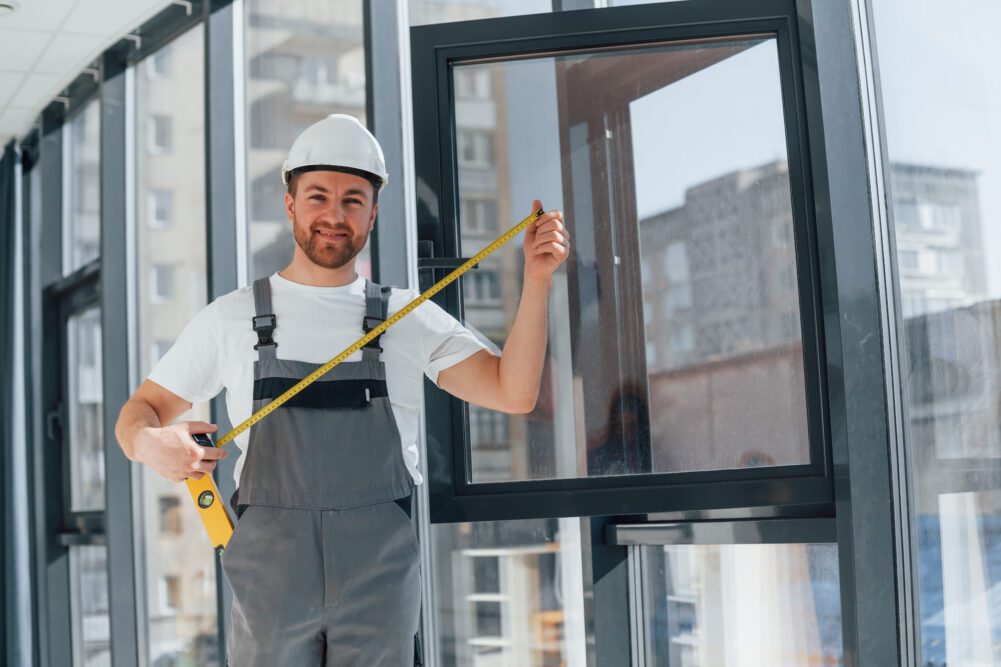Holding measure tape. Repairman is working indoors in the modern room